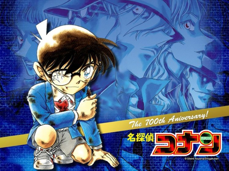 "Detective Conan 100th Anniversary promotional artwork showing the young detective character Conan Edogawa with his signature glasses and bow tie, with other characters in the background"